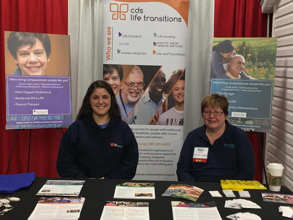 Two CDS employees sitting at a CDS table sharing information about what CDS has to offer