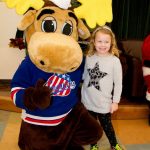 Little girl smiling and posing with the Amerks mascot